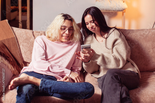 Happy young couple sitting on couch and looking at mobile phone