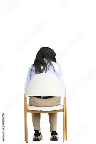 A girl in a blue shirt, on a white background, is sitting on a chair