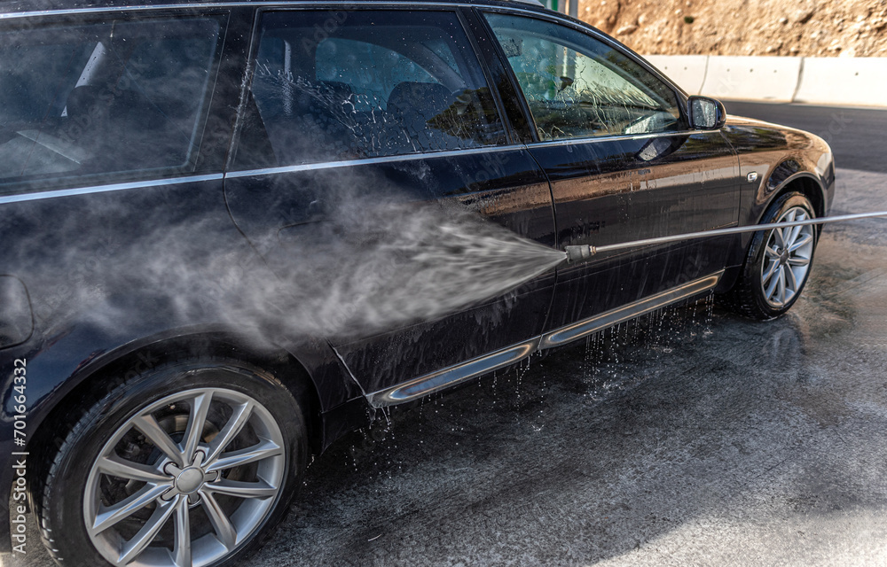 Car washing under the open sky. High-pressure washing car outdoors.