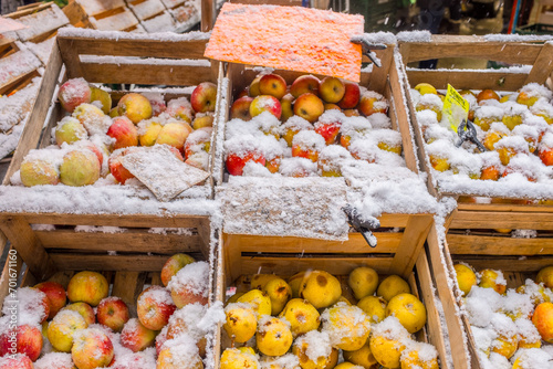Marktstand mit schneebedeckten Äpfeln in Obstkisten	

 photo