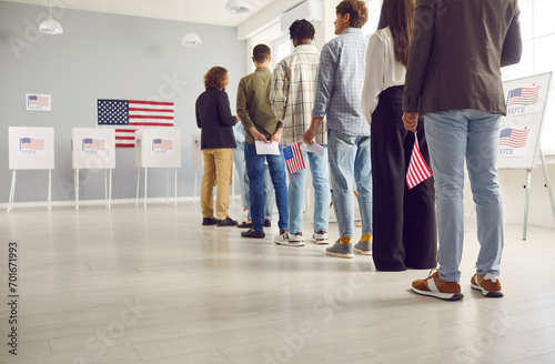 Group of american citizens people standing in polling station with USA flags in hands. Voters standing in a queue at vote center getting ballot paper. Election day and democracy concept. photo