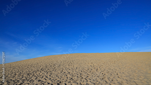 Dune landscape with Sandy beach at sea coast. Blue sky with white clouds. Sunset time.