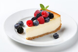 A slice of classic New York style cheesecake with berries and mint on top, on the white plate