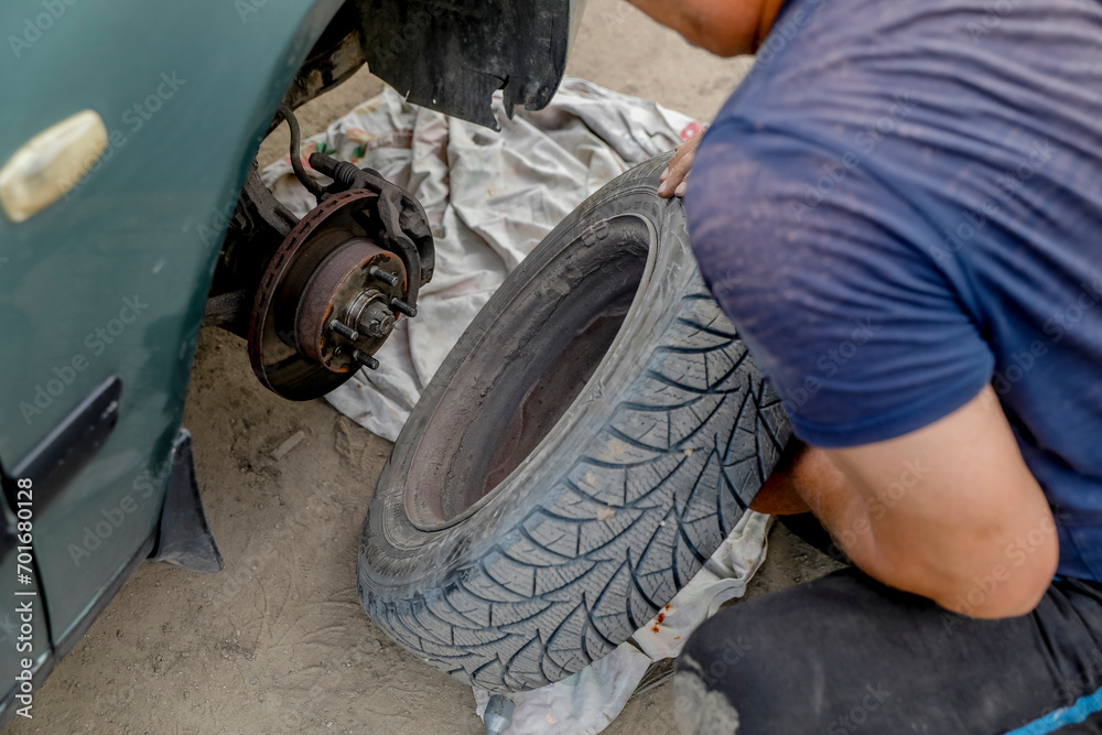 Man changing a tyre after a breakdown in a village near Soroca, Moldova Man changing a tyre after a breakdown in a village near Soroca, Moldova