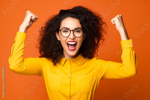 Woman with glasses and yellow shirt is raising her arms. photo