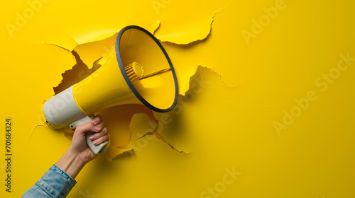 megaphone trough ripped paper on yellow background, marketing concept photo