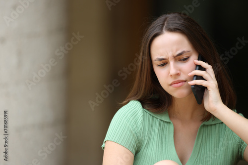 Confused woman talking on phone outdoors