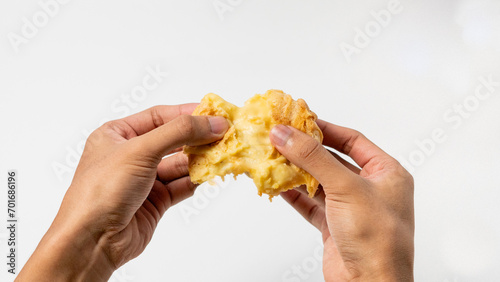 two hands are splitting a Vanilla eclair isolated on a white background
