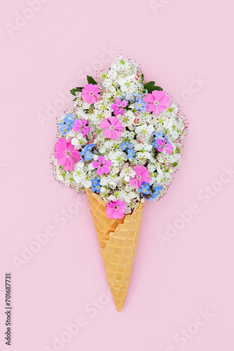 Surreal hawthorn blossom, forget me not and rose campion flower ice cream cone concept. Fun edible food art for logo, gift tag, birthday, mothers day, holiday vacation on pink background.