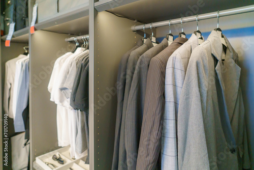 Men's suits and shirts hang in the closet..
