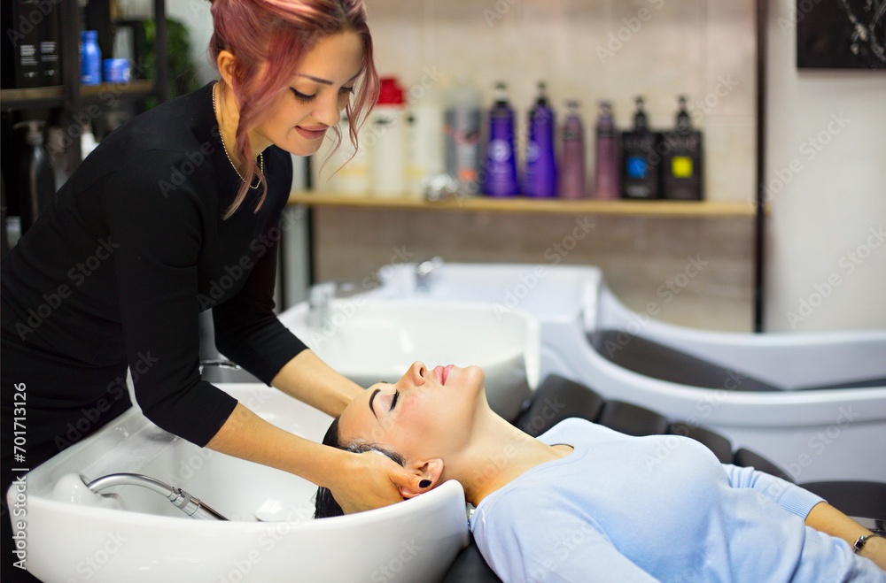 Gorgeous cheerful young woman enjoying head massage while getting her hair washed by a professional hairdresser Gorgeous cheerful young woman enjoying head massage while getting her hair washed by a professional hairdresser