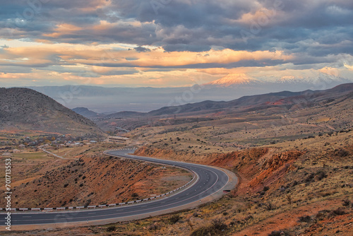 The S-curved road with Ararat mountains in the background at sunset. Travel destination Armenia