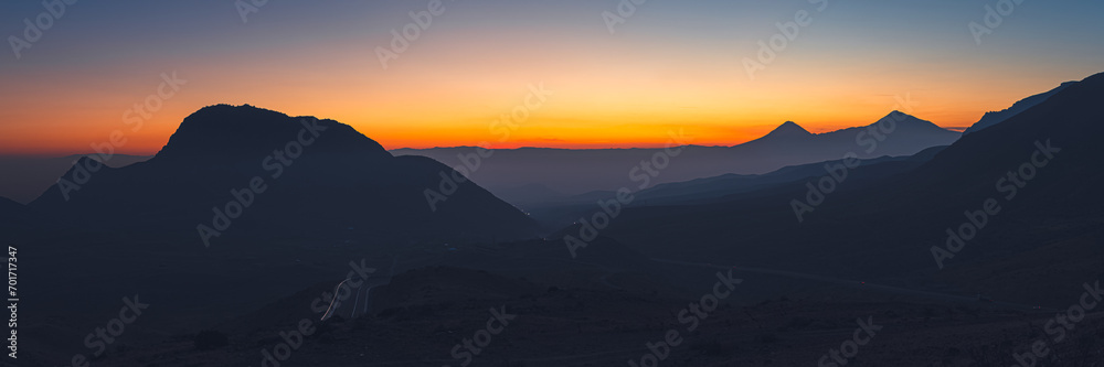 Wide angle panorama of colorful sunset over the Ararat mountains with mist over Ararat valley at winter. Travel destination Armenia