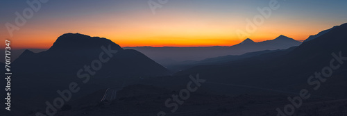 Wide angle panorama of colorful sunset over the Ararat mountains with mist over Ararat valley at winter. Travel destination Armenia