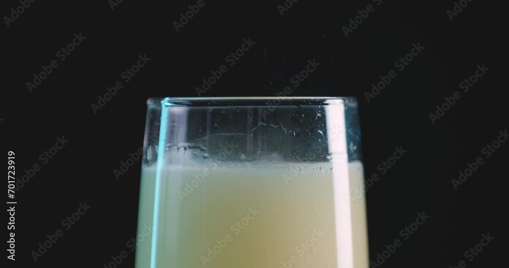Fizzy yellow soda refreshing liquid in glass against black background, close-up Fizzy yellow soda refreshing liquid in glass against black background, close-up