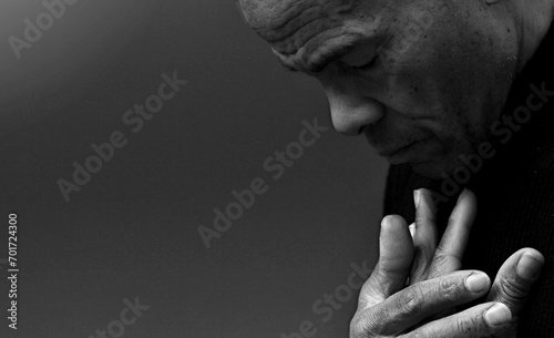 man praying to god with hands together Caribbean man praying with black background with people stock photo
