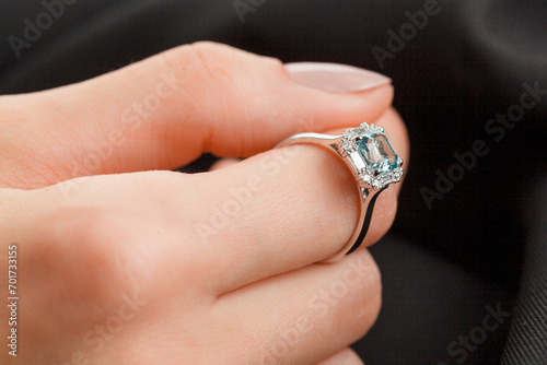 Beautiful female hand with gold ring with diamonds and emerald on gray background