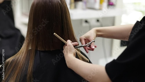 Unrecognisable hairdresser cutting female client hair with professional barber scissors and comb and making stylish haircut short bob hairstyle in beauty salon. Hair care, hair salon and hairstyling. photo