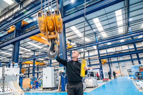 Worker using an industrial crane in a logistics factory