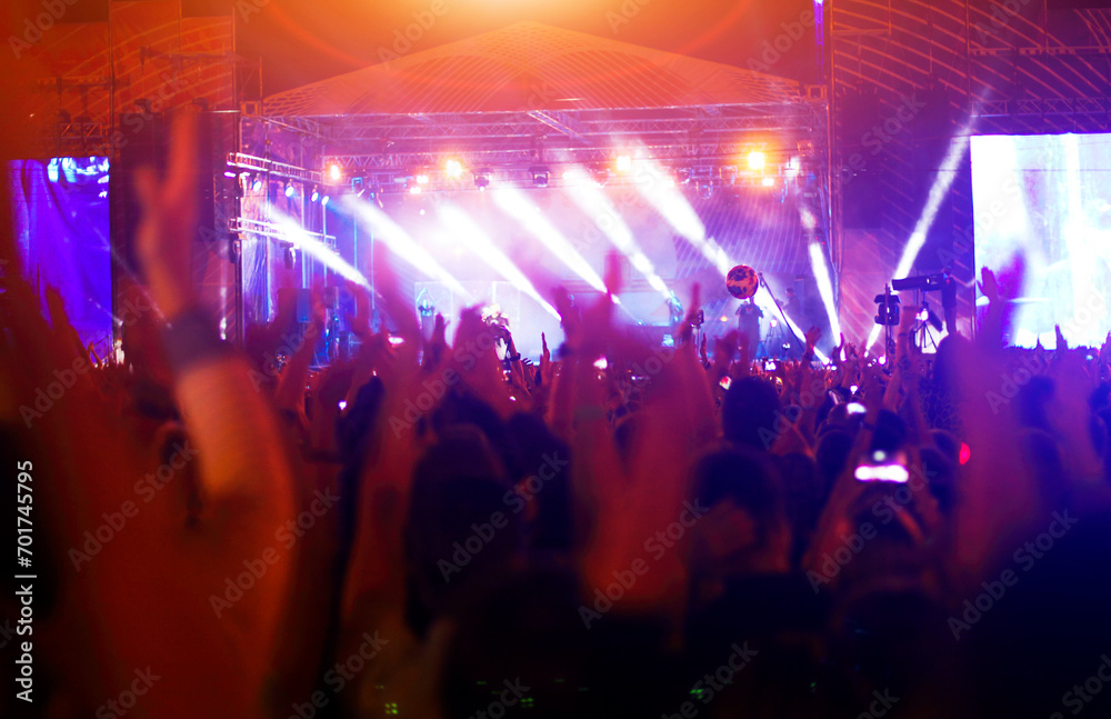 Silhouettes of concert crowd in front of bright stage lights