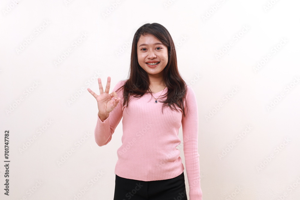 Smiling pretty young asian girl standing while showing okay hand gesture. Satisfied recommended concept. Isolated on white background Smiling pretty young asian girl standing while showing okay hand gesture. Satisfied recommended concept. Isolated on white background