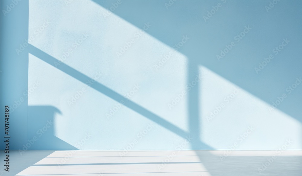 Obraz premium Sunlight casting soft shadows on a minimalist light blue interior wall.