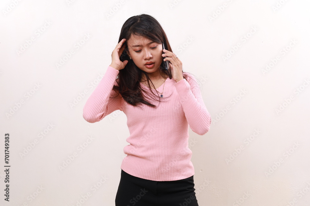 Stressed frustrated young asian girl standing while talking on the phone. Isolated on white background Stressed frustrated young asian girl standing while talking on the phone. Isolated on white background