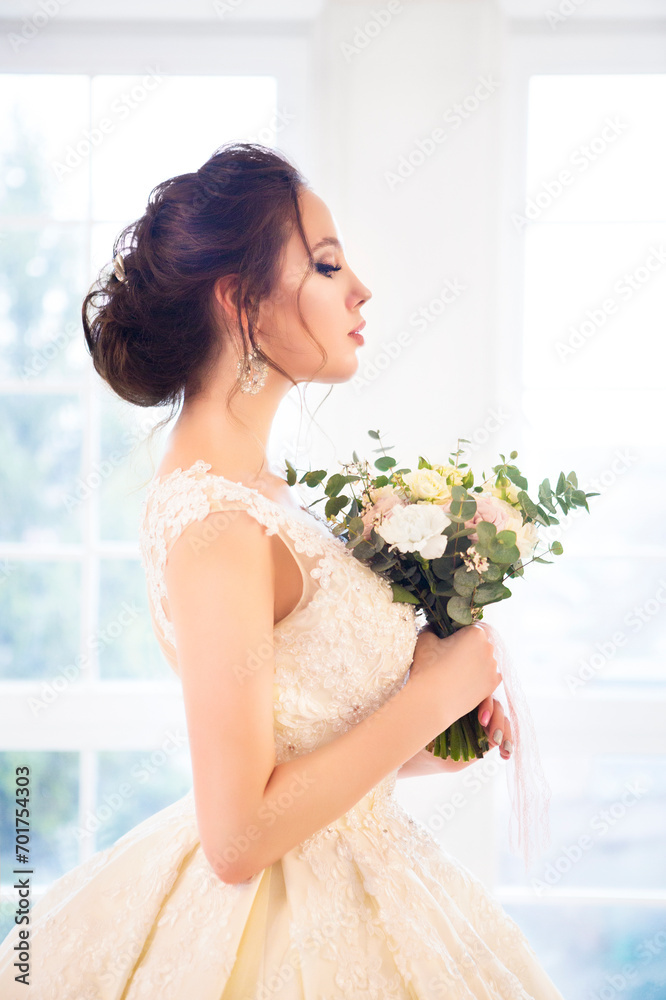 Beautiful brunette woman with bouquet posing in a wedding dress Beautiful brunette woman with bouquet posing in a wedding dress