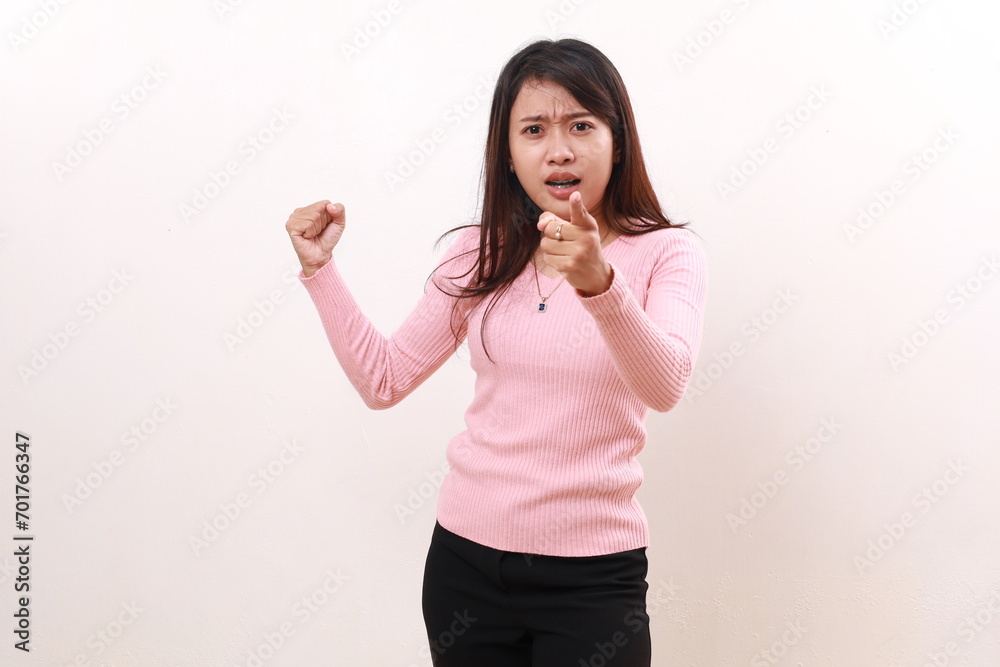Angry young asian girl standing clenching hand while pointing at the camera. Isolated on white background Angry young asian girl standing clenching hand while pointing at the camera. Isolated on white background