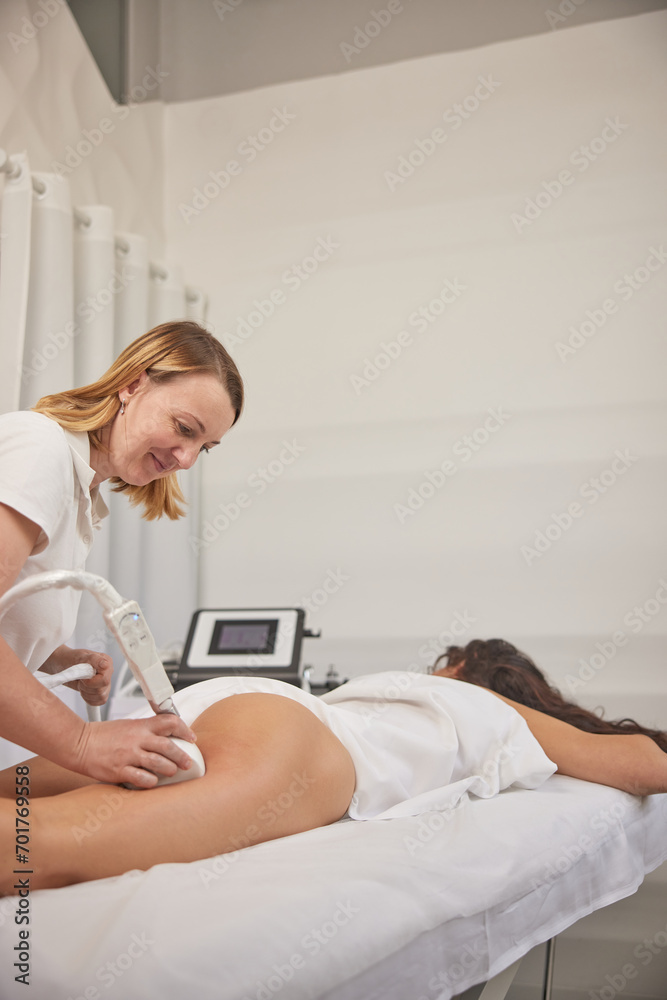 electroporation massage, body correction, beauty procedure. Young woman providing beauty services, body shaping, masseurs performing vacuum roller massage on clients, figure correction, anti-cellulite electroporation massage, body correction, beauty procedure. Young woman providing beauty services, body shaping, masseurs performing vacuum roller massage on clients, figure correction, anti-cellulite