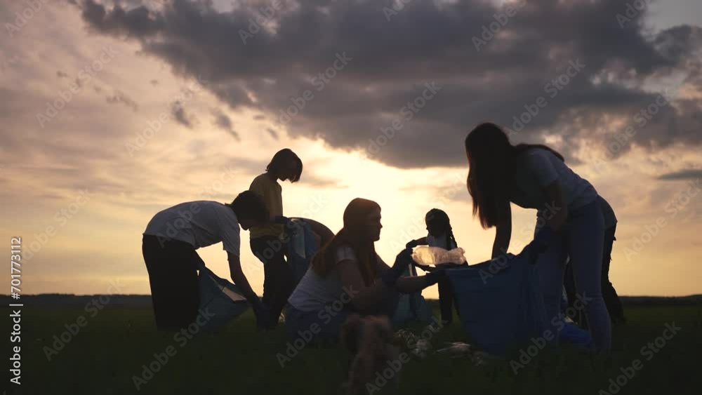 people collect garbage in bags at sunset. garbage collection help concept. a group of volunteers helps the environment fight waste. friendly team work together lifestyle and clean up nature together