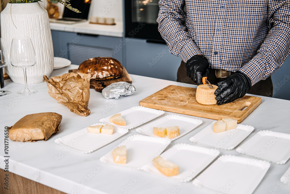 Caterer Preparing Cheese Platters for an Event. Professional caterer arranges various types of cheese on plates, wearing gloves for hygiene while preparing for a gourmet event. Caterer Preparing Cheese Platters for an Event. Professional caterer arranges various types of cheese on plates, wearing gloves for hygiene while preparing for a gourmet event.