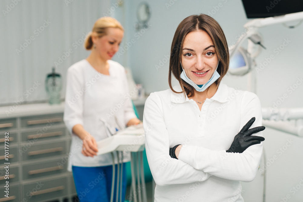 Fototapeta premium Woman doctor dentist on the background of a modern dental clinic. Work of a doctor and nurse in dentistry. The concept of advertising dental services and healthy teeth.