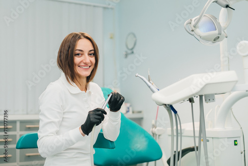 Young female dentist holds instruments in her hands in the interior of a modern dental clinic. The concept of professional activity  dental instruments and services.