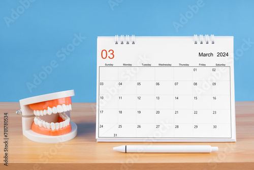 March monthly desk calendar for 2024 year and model dentures on the table.