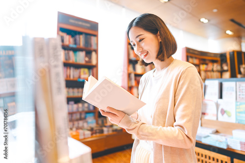 Portrait of young adult southeast asian woman reading book at bookstore shop photo