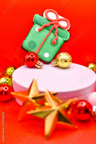 Imagen vertical de una galleta de navidad en una plataforma blanca con adornos de navidad sobre un fondo rojo aislado navideño 