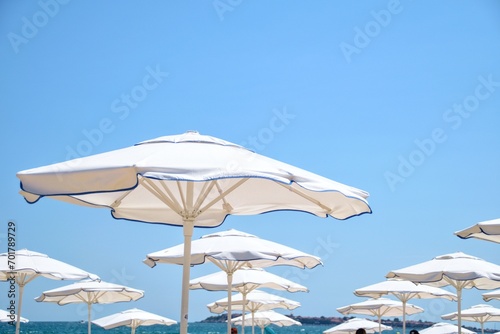 White beach umbrellas on the seashore against the sky. Travel and recreation at sea.