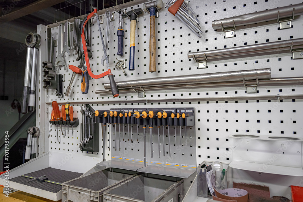 Square slot screwdrivers, keys and various tools hang on a rack in a locksmith workshop.