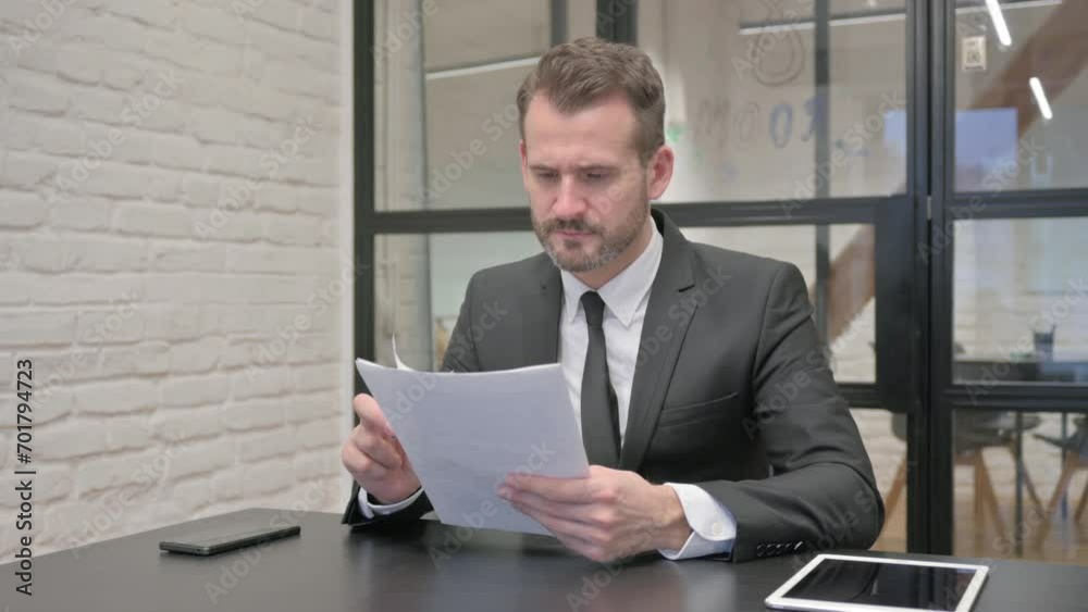 Middle Aged Businessman Reading Documents at Work Middle Aged Businessman Reading Documents at Work