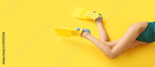 Beautiful young woman in swimsuit and paddles on yellow background with space for text