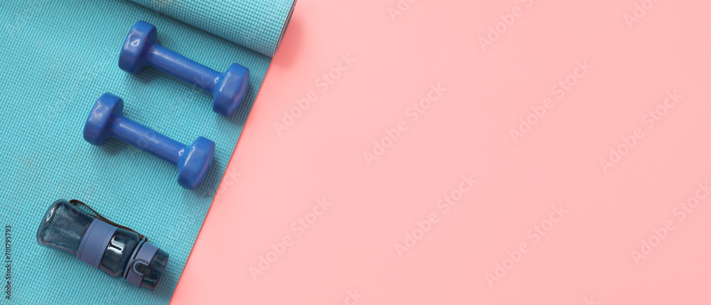 Yoga mat, dumbbells and bottle for water on pink background with space for text Yoga mat, dumbbells and bottle for water on pink background with space for text