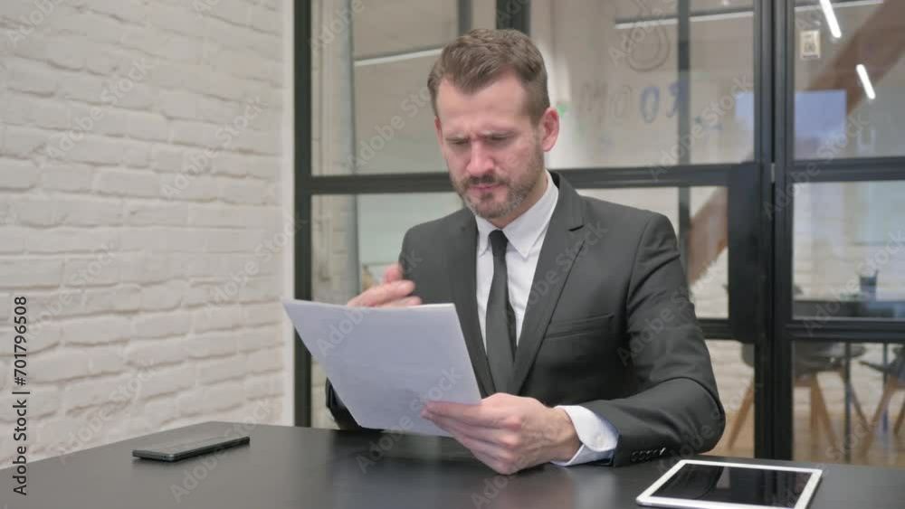 Middle Aged Businessman Feeling Upset while Reading Contract Middle Aged Businessman Feeling Upset while Reading Contract