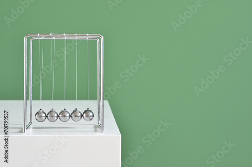 Newton's Cradle on table near green wall