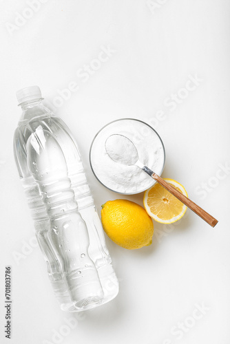 Bottle of vinegar, baking soda and lemons for cleaning on white background