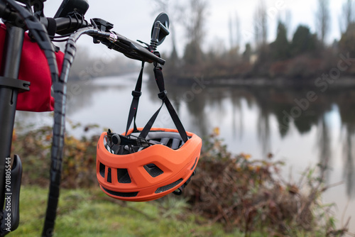 Orange bicycle helmet hangs from handle bar of bike