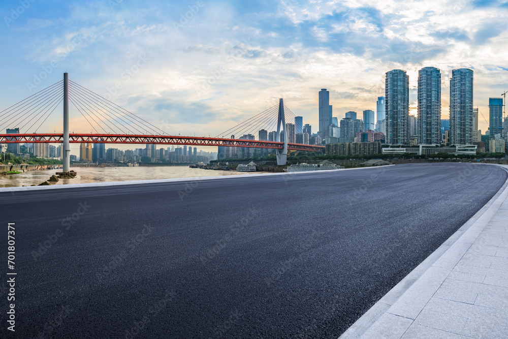 Fototapeta premium Empty asphalt road and city buildings skyline at sunset