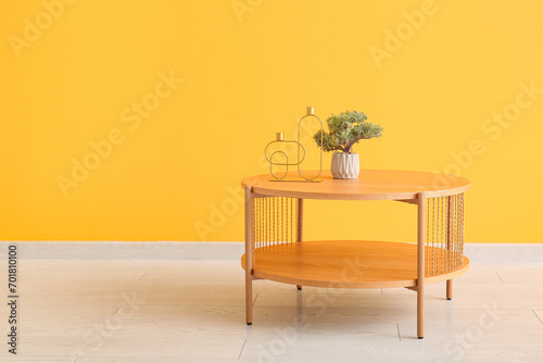 Fototapeta Naklejka Na Ścianę i Meble -  Wooden coffee table with bonsai tree and decorative candle holders near orange wall