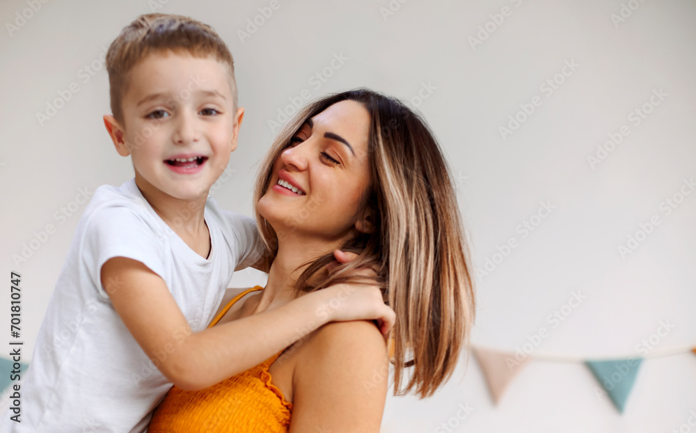 Young happy family loving mother and her child son having fun together at home, playing and laughing