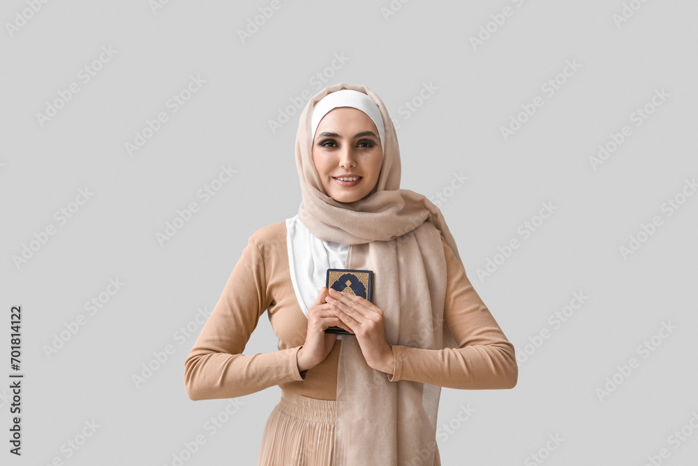 Young Muslim woman with Koran on light background. Islamic New Year celebration Young Muslim woman with Koran on light background. Islamic New Year celebration